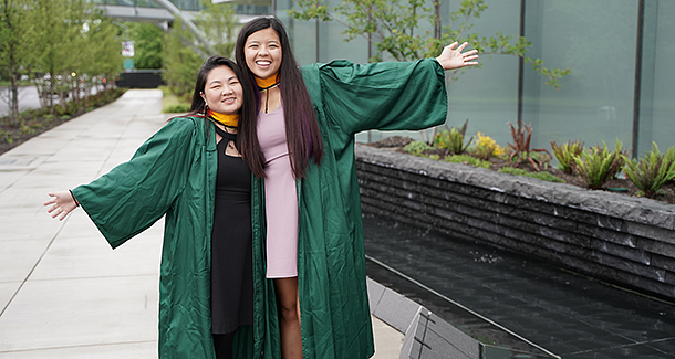 Karly Knox on left and Alexi Overland on right outside the Knight Campus building in graduation robes