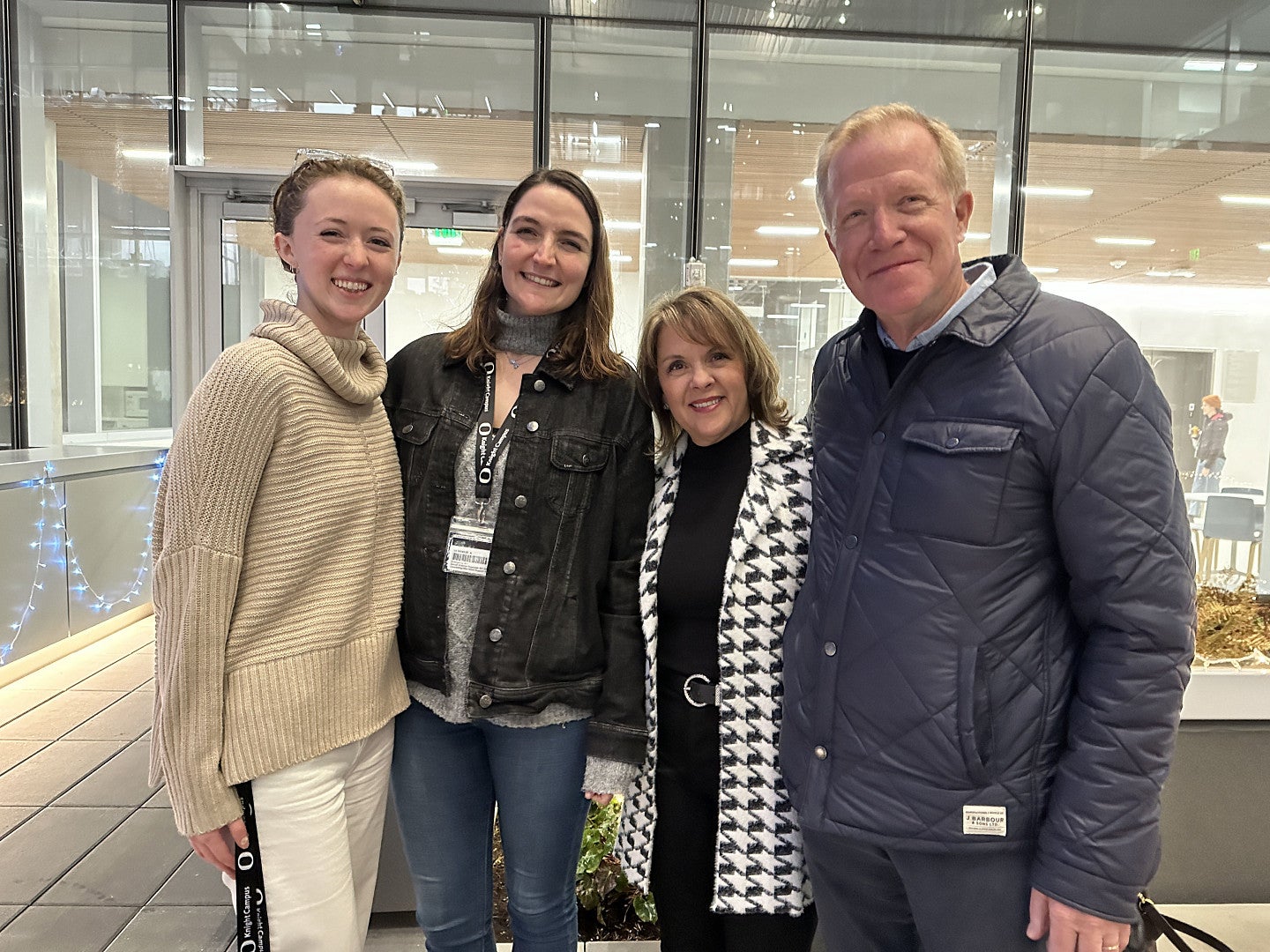 Three women and one man stand together for a photo