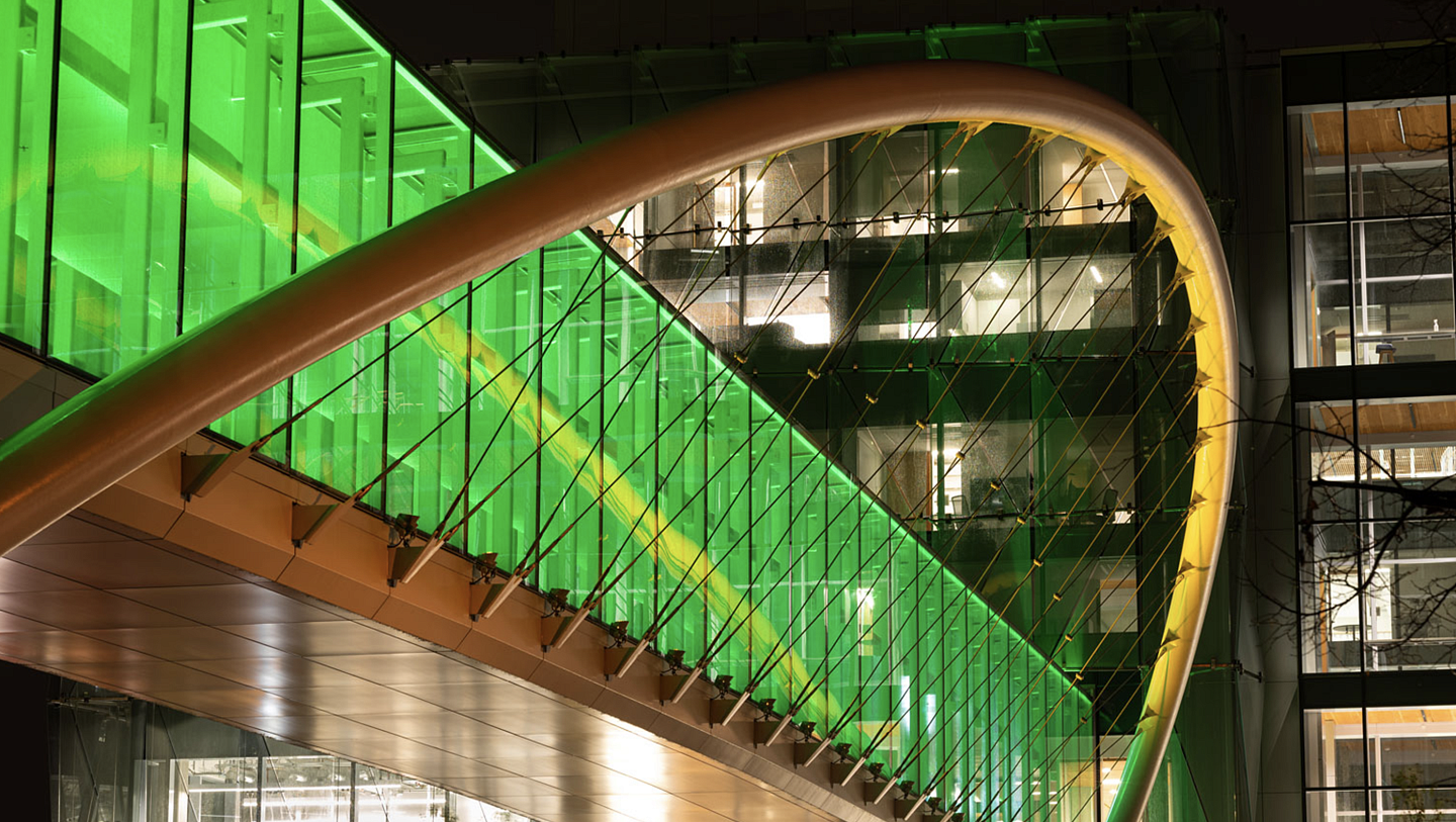 A pedestrian bridge lit up with green lights