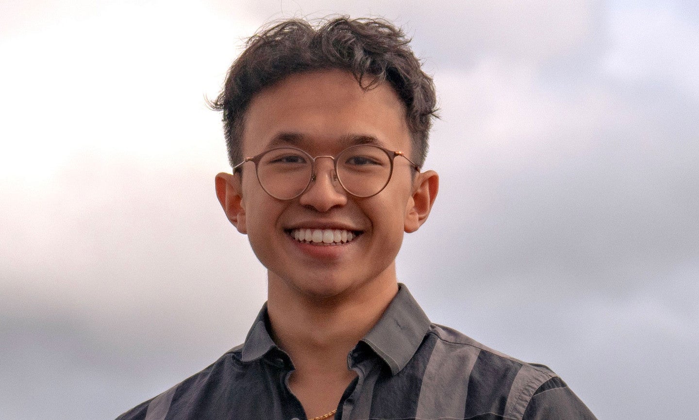 Knight Campus Undergraduate Scholar Ethan Dinh posing against a gray sky