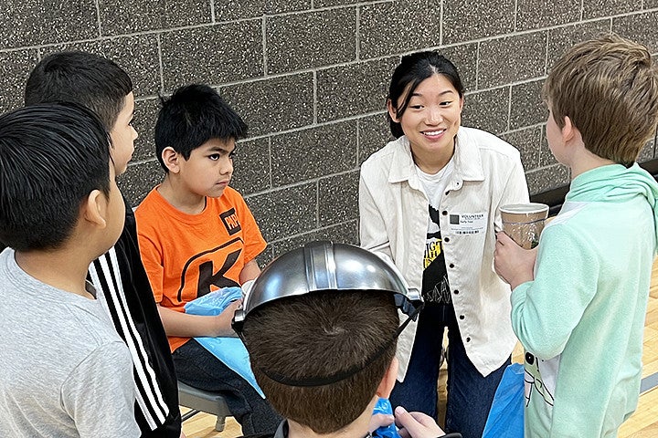 A woman explains science to a group of kids