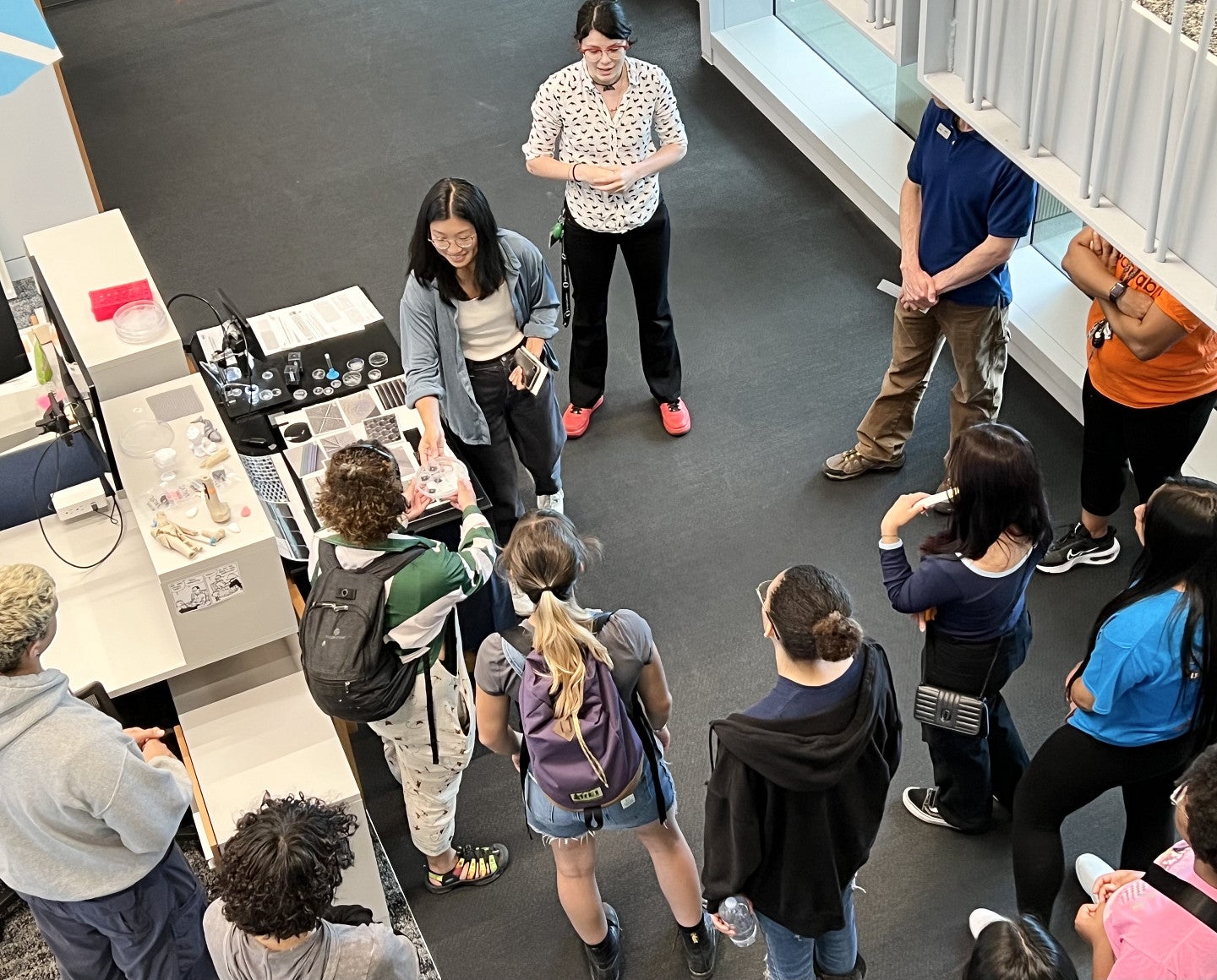 Two college students give a tour of a lab to a group of high school students