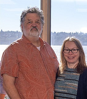 A man and woman stand in front of a window