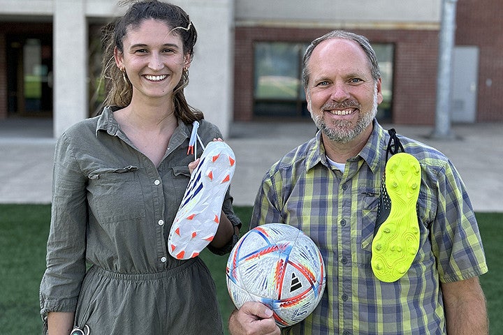 Two people with soccer cleats and a soccer ball