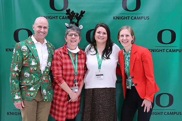 Four adults pose in front of a green background