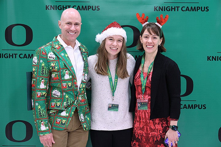 Three adults posing in front of a green background