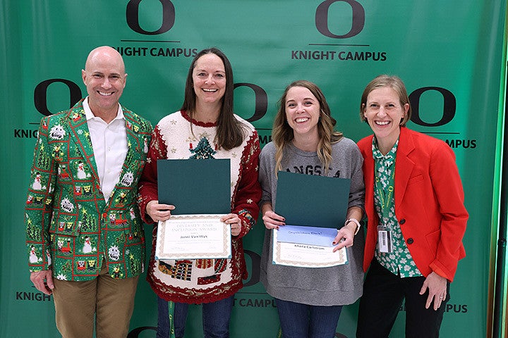 Four adults posing with awards