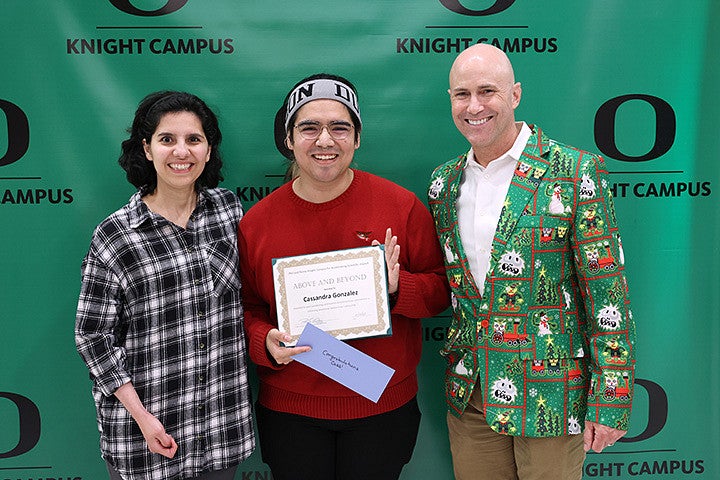 Three adults pose in front of a green background