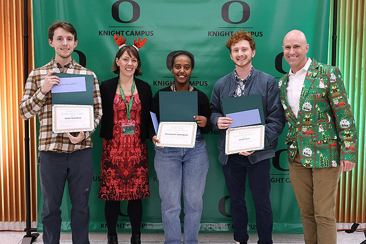 Adults pose holding award certificates