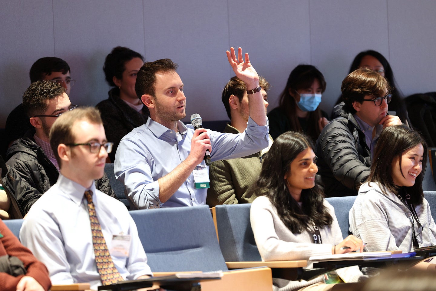 Students in seminar room with one speaking into microphone