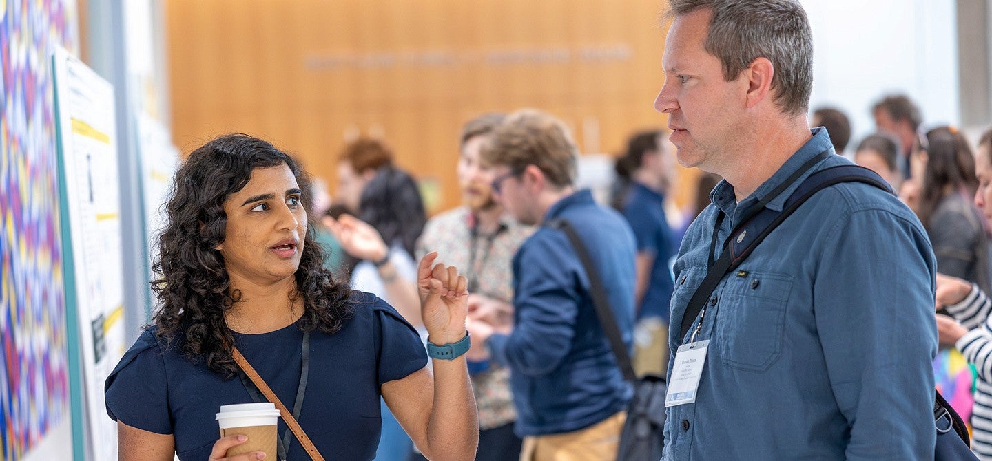 Two peopel standing before a scientific poster talking