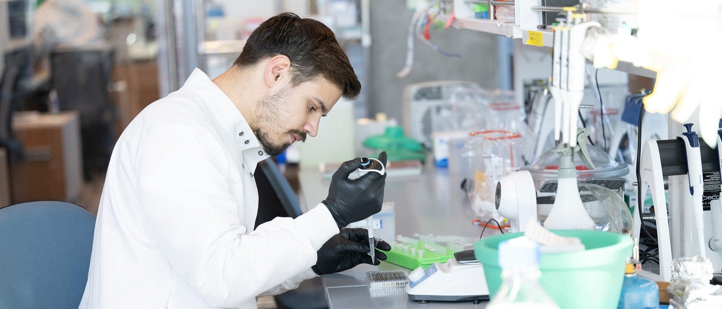 Environmental portrait of Yan Carlos Pacheco using a pippette in the lab