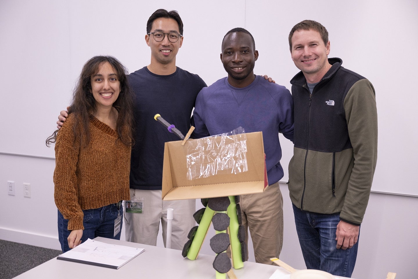 Anika Moorjani, Andy Huang, David Dzamesi, and Russell McLoughlin posing with a shared design project during Impact Week