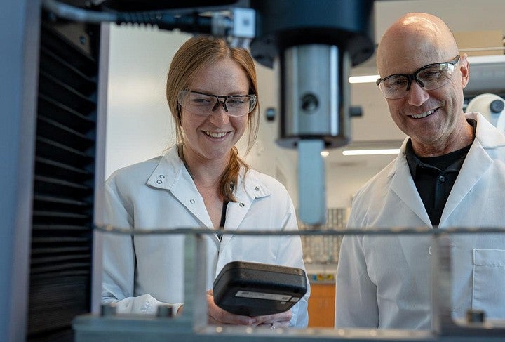 Two people in lab coats smiling