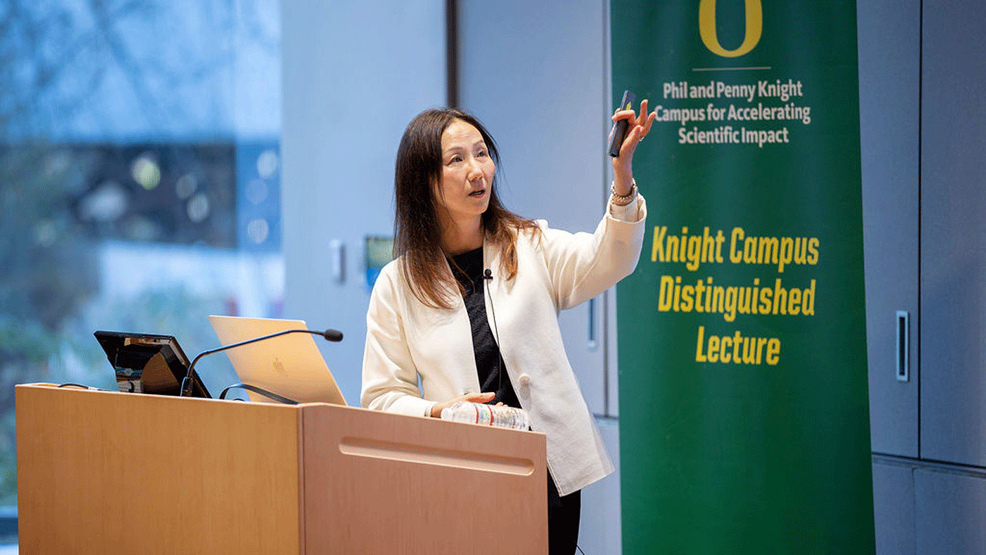 Woman at lectern with Phil and Penny Knight Campus for Accelerating Scientific Impact Distinguished Lecture Series banner behind her