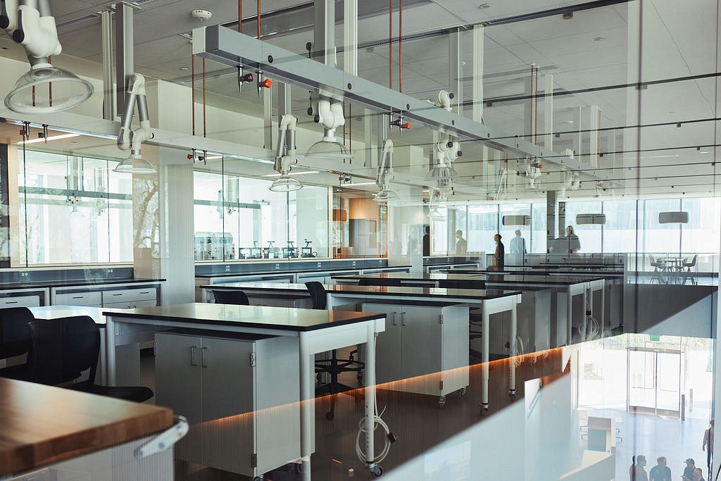 glass walls, with lab spaces for teaching. white tables with black bench tops