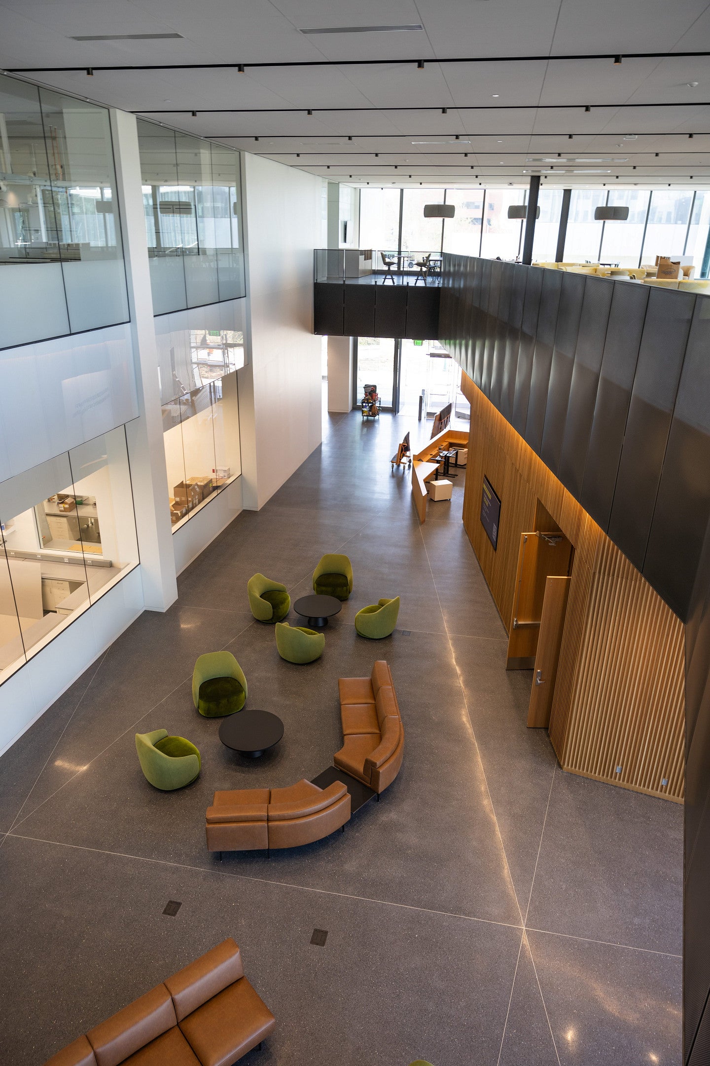 the lobby, and biofoundry, in building 2. Glass, wood walls, black steel railings and leather and green upholstery furniture