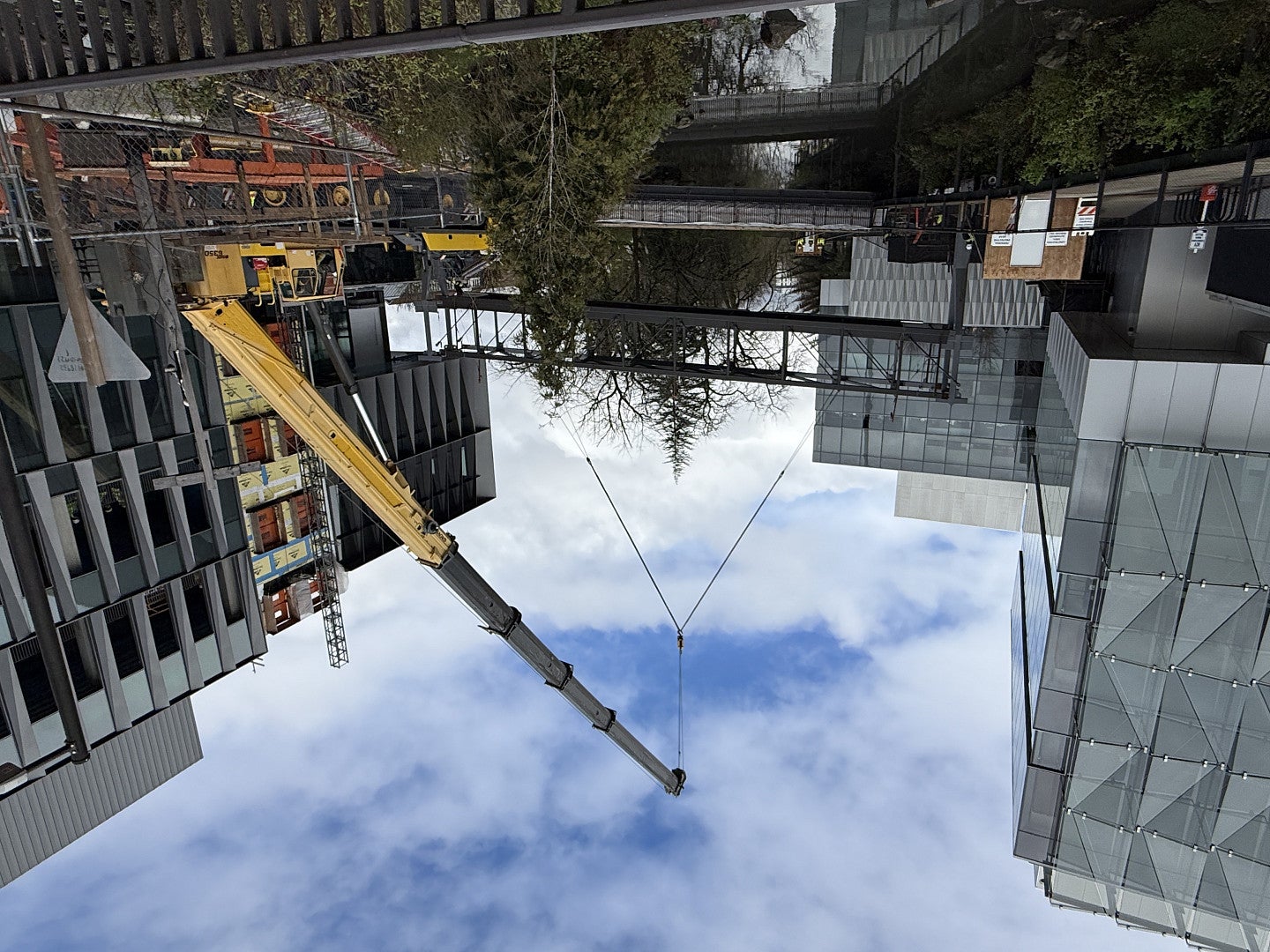 construction crew installing a skydbridge between two buildings with a crane
