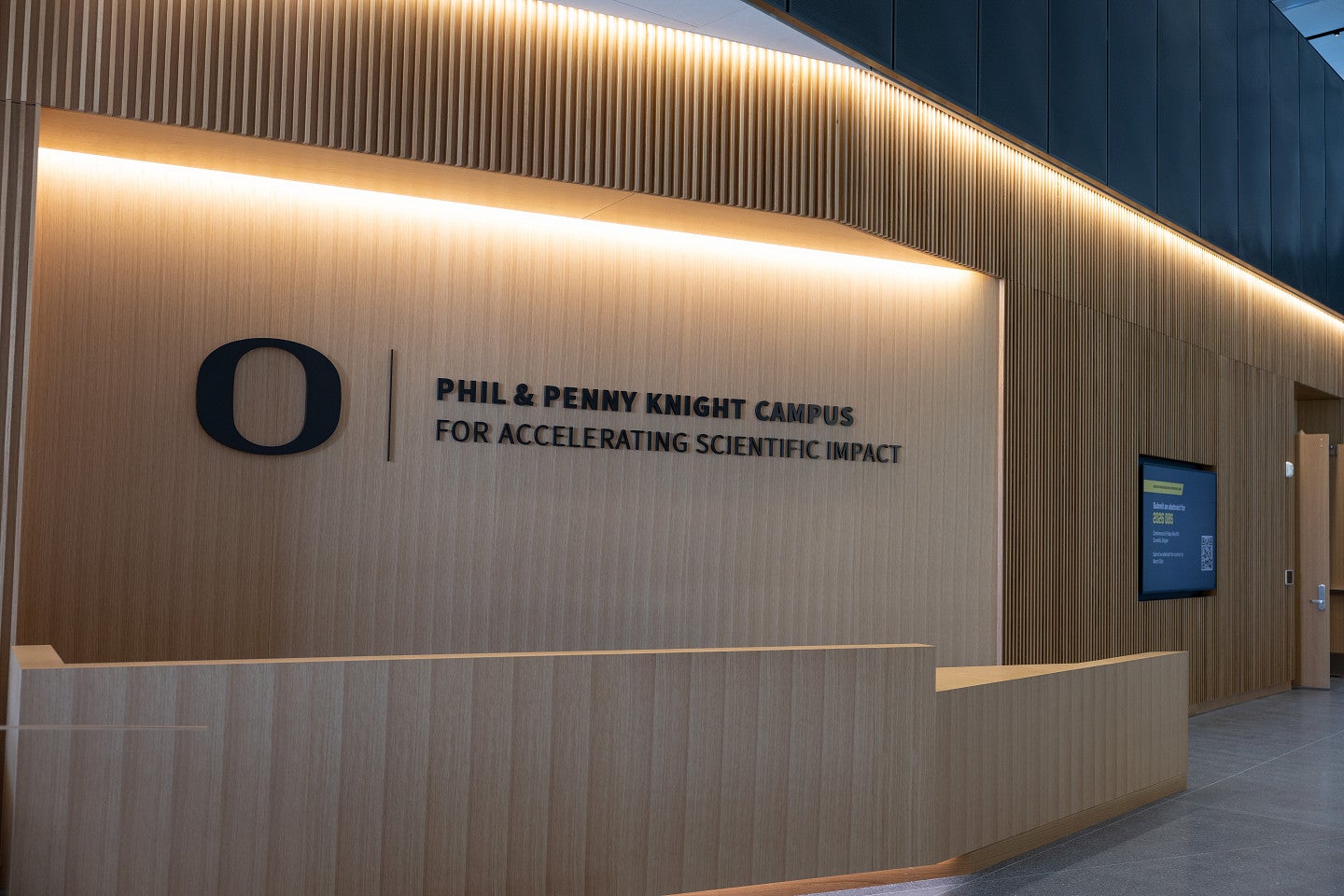 Wooden wall with a black sign with the 'O' and "Phil and Penny Knight Campus For Accelerating Scientific Impact"
