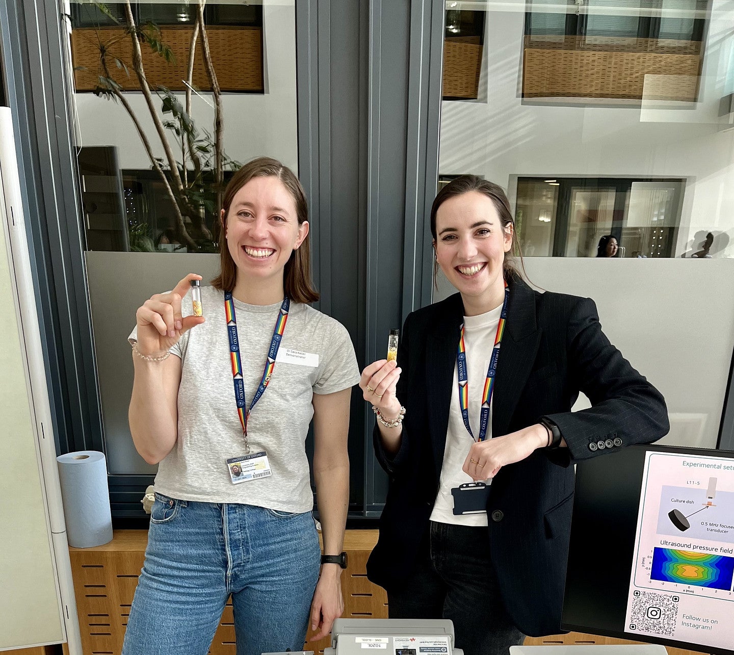 Sara Keller, with another woman holding a small glass vial in front of some equipment