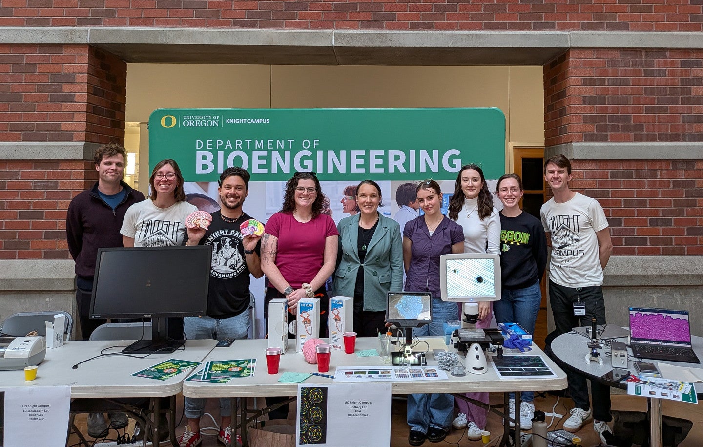 People standing in front of a banner that reads 'Bioengineering' wtih tables that have monitors and handouts