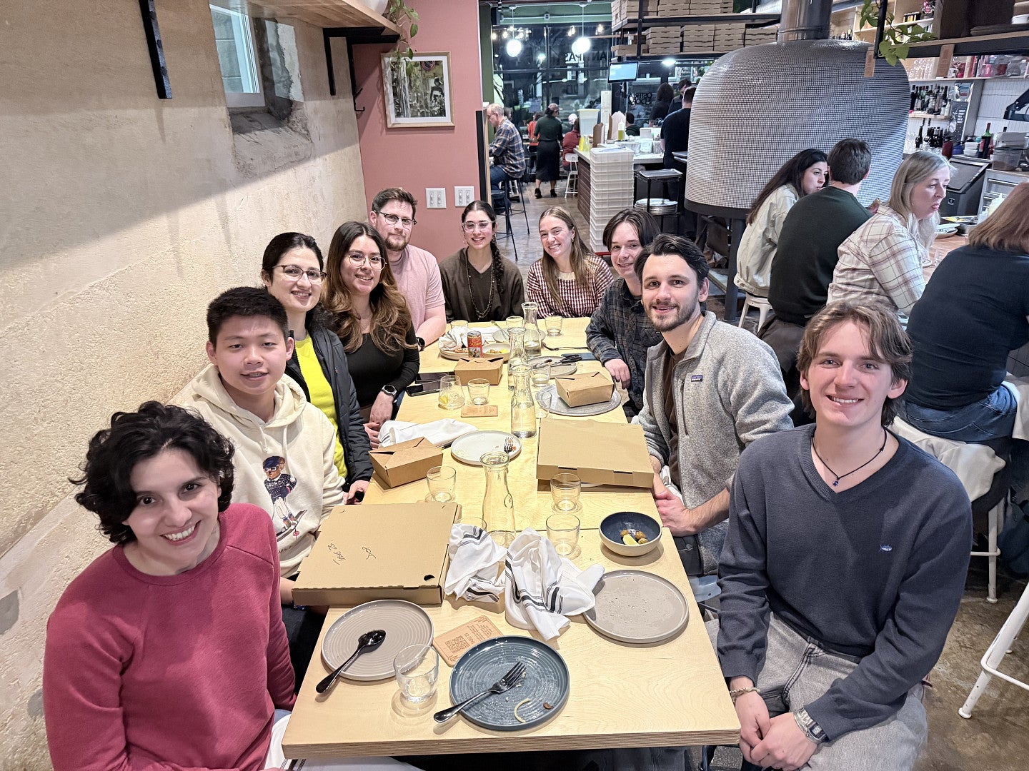 a group of people out at restaurant, all sitting around the table, and looking at the camera
