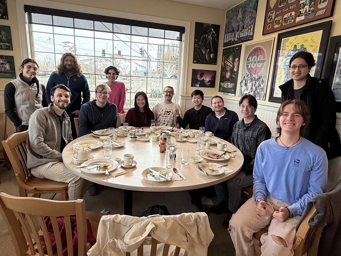 group of people around a round table, with lots of framed art behind them. 
