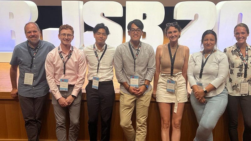 Group of people standing in front of letters BJSB