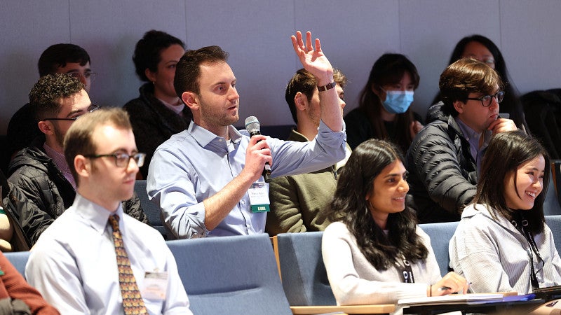 Students in seminar room with one speaking into microphone