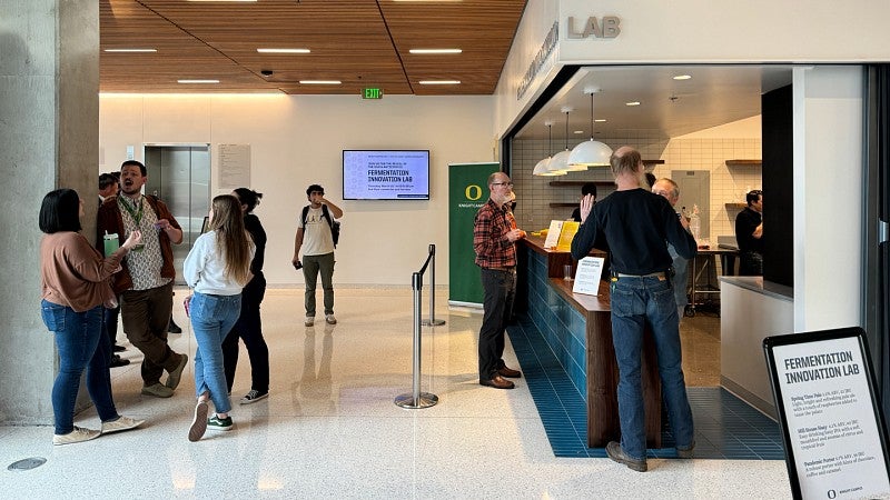 People mingling in front of a bar with a sign that reads Brewing Innovation Lab