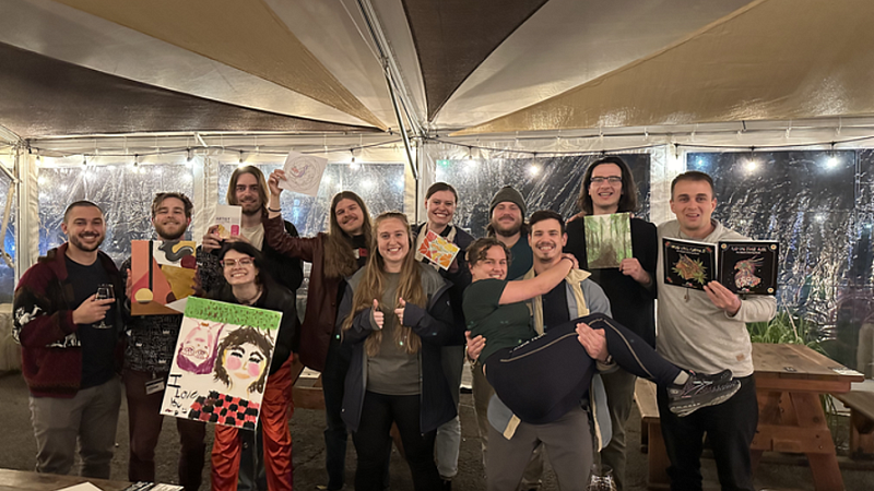 Group of people posing under a tent at night with art projects