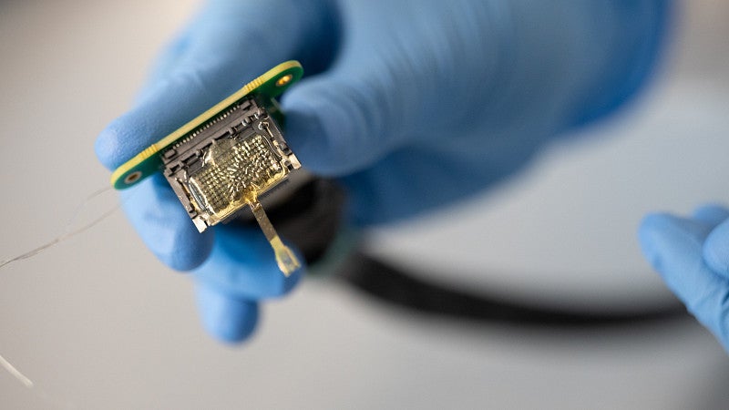 a thin array electrode, shown with electrical boards and someone holding with a blue glove, in the Deku lab at the Knight Campus