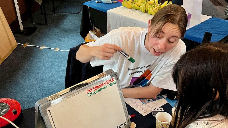 Sara Keller explaining and drawing something on a whiteboard for a child