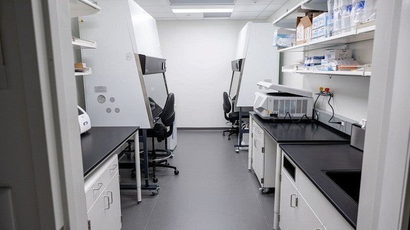 An empty room as a lab space with glass vials, a black counter top, and two fume hoods