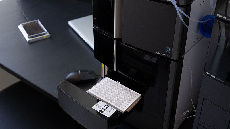 a computer monitor with a machine next to it that has glass vials, with tubes hanging out