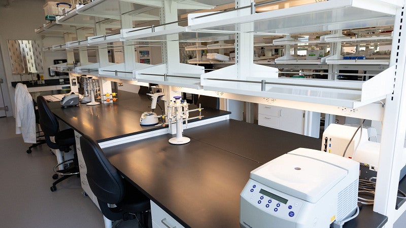 Empty lab space with black benches, and white/grey equipment