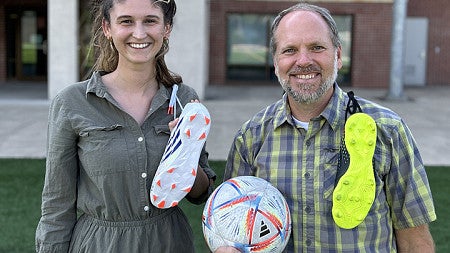 Two people with soccer cleats and a soccer ball