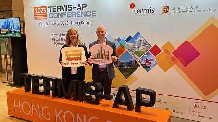 man and a woman in front of a Termis AP Conference backdrop