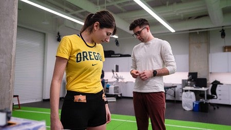 Person in yellow orange shirt with the words "oregon" and person in white shirt in background