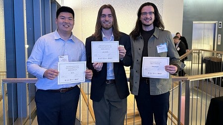 Three people standing with award certificates