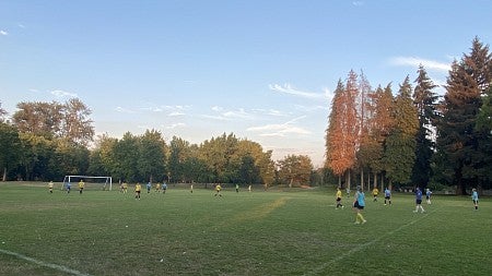 Knight Campus graduate students playing soccer in a field on a fall day