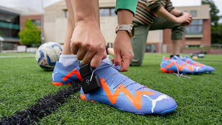 someone tying up a soccer cleat, attached with a sensor. 