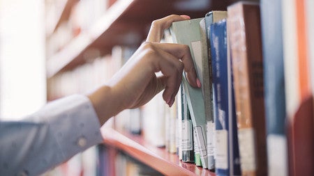a hand pulling a library from a bookshelf. 