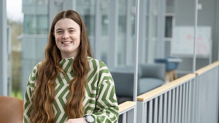 headshot of a woman with long brown hair, in a green and white sweater