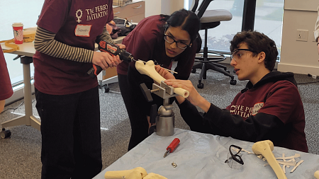 Student drills into artifical bone as two students look on