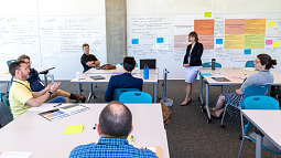 Group of people in a working meeting with colorful sticky notes and writing on white board