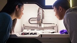 Two people looking at scientific equipment in a lab