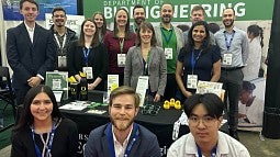 Group of people standing in conference hall before a backdrop that includes the University of Oregon and Knight Campus logos and the wording "Department of Bioengineering."