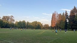 Knight Campus graduate students playing soccer in a field on a fall day