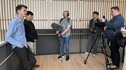 Scientists on left being interviewed by reporters form media outlets on right